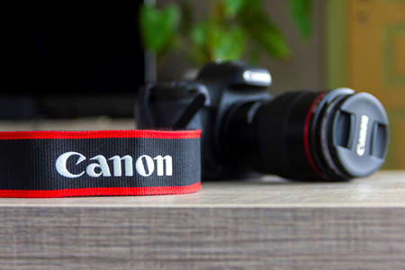 Brecht, Belgium - April 30 2020: A portrait of a camera strap of the canon company lying on a table with in the background a clurred canon camera.のeditorial素材