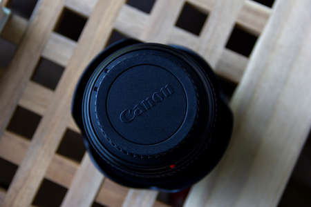 Brecht, Belgium - June 20 2020: A closeup portrait of the back lid of a canon camera lens containing the logo of the company. The lens is standing upside down on a wooden table.のeditorial素材