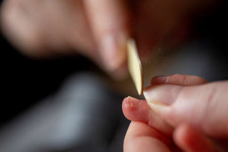A close up portrait of a mother filing the nails of a small baby hand after clipping them. The...
