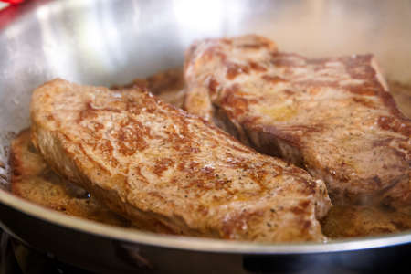 A portrait of minute beef steaks, which are thin pieces of meat. The food is cooking in a frying pan...