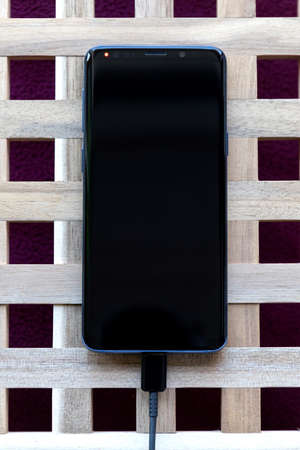 Brecht/Belgium - April 1 2020: A top down portrait of a smartphone with a USB cable in its port...