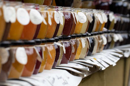 BEERVELDE, BELGIUM - MAY 12 2019: A close up portrait of a market stall selling pots of jam in all kinds of flavors. They have fruits and mixed fruits all nicely displayed and portioned in glass pots with a metal lid.のeditorial素材