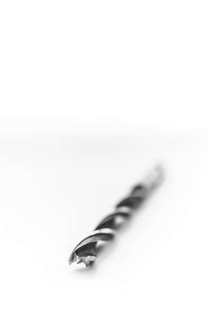 A black and white studio portrait of a metal high speed steel wood drill bit lying down with a white background. The tool is used by a carpenter for drilling holes in woodwork with a drilling machine.の写真素材