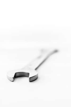 A black and white art portrait of an open end wrench lying on isolated on a white background. The metal tool is ready to use for construction work or repairing something.の写真素材