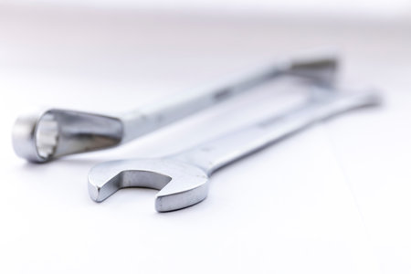 A portrait of two metal tools, a open end and a box end wrench lying next to each other on a white background. The tools are ready to use in construction or for repairing something.の写真素材