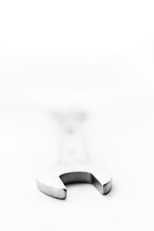An art black and white portrait of a double open end wrench lying on a white background with the head pointing straight towards the camera.の写真素材