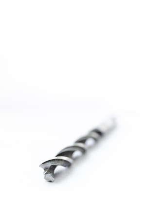 A black and white art studio portrait of a spiral high speed steel wood drill bit on a white background. The metal tool is used to drill holes into wood for repair or building or construction work.の写真素材