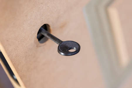 A portrait of a black design key in an unfinished mdf door. The design part of the key hole is not installed yet and the door is not painted yet. The lock is already present in the door.の写真素材
