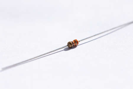 A close up portrait of a 330 ohm resistor with a 5% tolerance. The electric partis isolated on a white background and is ready to be used in an electronic circuit or soldered on a PCB.