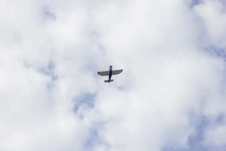 A private sports plane flying high in a cloudy sky. The airplane is shot from below.の写真素材