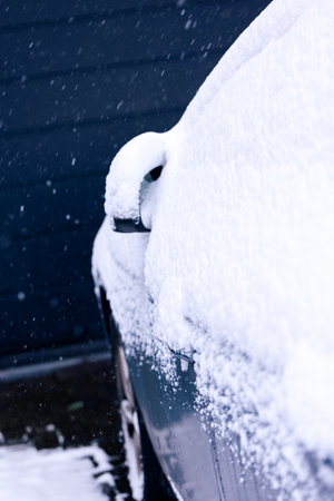 A side mirror and side window of a car at the driver side covered in white snow during winter season. In order to start driving the driver will have to clear the snow or wait for it to melt.の写真素材