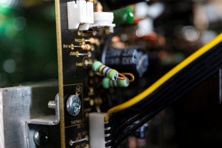 A close up portrait of some resistors on a black circuit board in an open electronic device. on the...