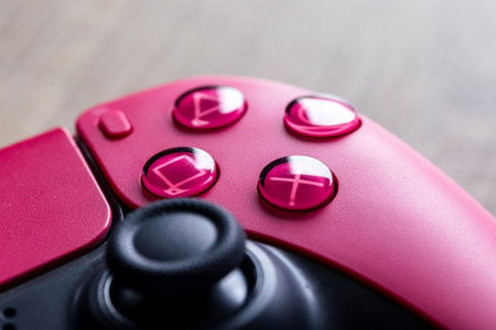 Brecht, Belgium - January 26, 2023: A close up portrait of the classic buttons of a sony playstation 5 cosmic red wireless controller. The triangle, circle, square and cross button are visible.のeditorial素材