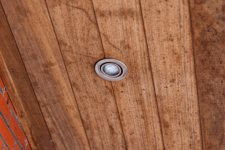A portrait of a weather sealed light spot put in the wooden planks of a roof overhang. The lamp has turned off.の写真素材