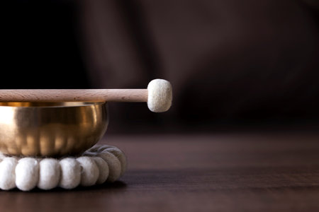A portrait of half of a tibetan singing bowl with a mallet on it and negative space to the right. The himalayan bowl is used for stress relief, relaxation and meditation.の写真素材
