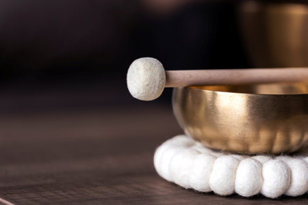 A close up portrait of half of a tibetan singing bowl with a mallet on it and 7negative space to the left. The himalayan bowl is used for stress relief, meditation and relaxation.の写真素材