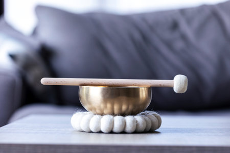 A close up of a himalayan bowl or tibetan singing bowl, with a mallet lying on top of it to make a relaxing sound. The object is used for meditation, relaxation and therapy to relieve stress.の写真素材