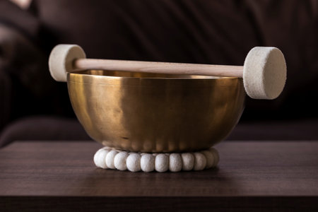 A large himalayan bowl, also called a singing bowl, with a mallet lying on top of it to make a relaxing sound. The object is used for relaxation, meditation and therapy to relieve stress.の写真素材