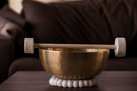 Portrait of a large himalayan bowl, also called a singing bowl, with a mallet lying on top of it to make a relaxing sound. The object is used for meditation, relaxation and therapy to relieve stress.の写真素材