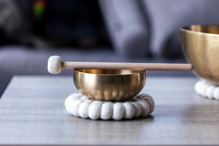 A close portrait of a tibetan singing bowl or himalayan bowl, with a mallet lying on top of it to make a relaxing sound. The object is used for relaxation, meditation and therapy to relieve stress.の写真素材