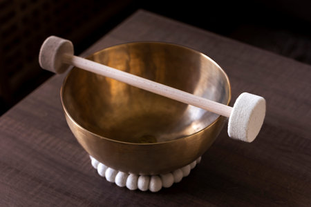 A closeup of a large himalayan bowl, also called a singing bowl, with a mallet lying on top of it to make a relaxing sound. The object is used for therapy, relaxation and meditation to relieve stress.の写真素材