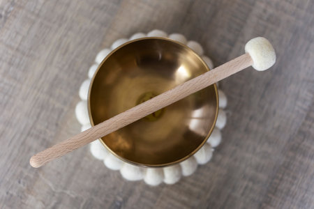 A portrait of a tibetan singing bowl or himalayan bowl, with a mallet lying on top of it to make a relaxing sound. The object is used for relaxation, meditation and therapy to relieve stress.の写真素材