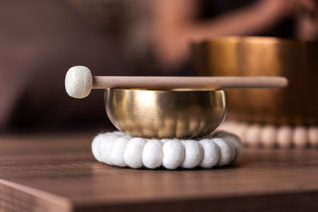 A close up of a tibetan singing bowl or himalayan bowl, with a mallet lying on top of it to make a relaxing sound. The object is used for therapy to relieve stress and relaxation, meditation.の写真素材