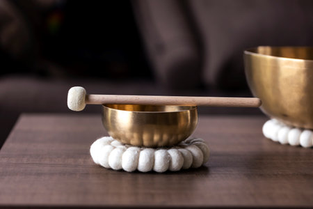 A portrait of a tibetan singing bowl or himalayan bowl, with a mallet lying on top of it to make a relaxing sound. The object is used for relaxation, meditation and therapy to relieve stress.の写真素材