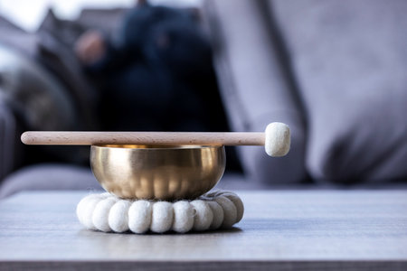 A portrait of a himalayan bowl or tibetan singing bowl, with a mallet lying on top of it to make a relaxing sound. The object is used for therapy to relieve stress and meditation, relaxation.の写真素材