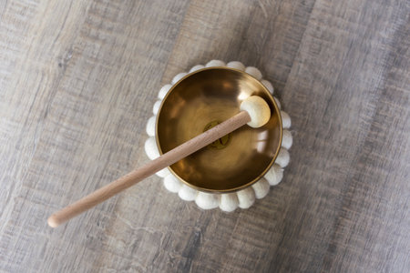 A portrait of a tibetan singing bowl, also called a himalayan bowl, with a mallet standing in it to make a relaxing sound. The object is used for therapy to relieve stress and relaxation, meditation.の写真素材