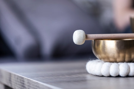 A close up portrait of half of a tibetan singing bowl with a mallet on it and empty space to the left. The himalayan bowl is used for stress relief, relaxation and meditation.の写真素材