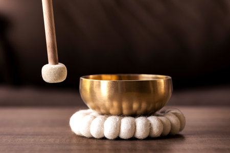 A portrait of a mallet about to hit a Tibetan singing bowl or himalayan bowl to produce a relaxing sound for meditation, relaxation and to relieve stress. It is an alternative medicine.の写真素材