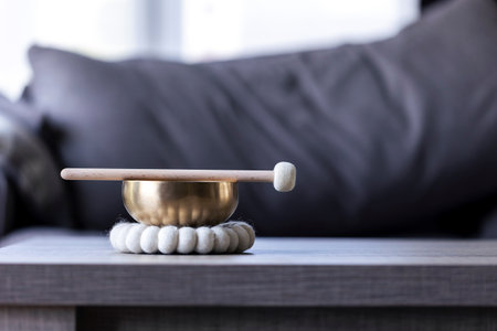 A portrait of a himalayan bowl or tibetan singing bowl, with a mallet lying on top of it to make a relaxing sound. The object is used for relaxation, meditation and therapy to relieve stress.の写真素材