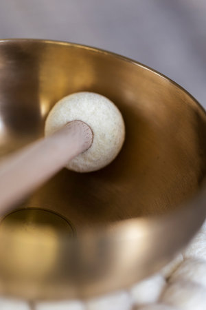 A close up portrait of the mallet lying in a tibetan singing bowl or himalayan bowl. This alternative medicine method is used for relaxation, meditation and therapy for stress relief.の写真素材