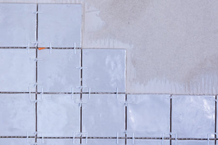 A portrait of an unfinished tile wall, with plastic white joint spacers still in the junctures and...