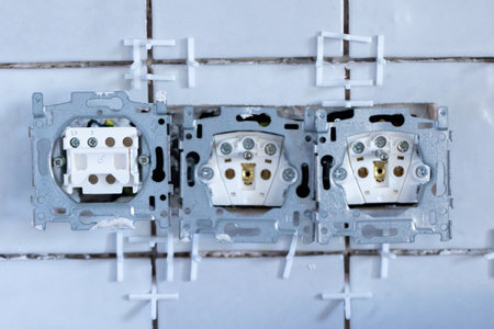 A close up portrait of two electric wall sockets and one light switch without their protective caps...