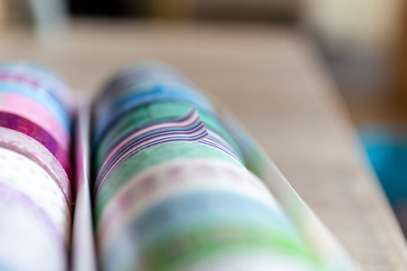 A portrait of colorful washi tape in different patterns and colors in a box. The decorative rolls are ready to use to decorate a gift, gift or post card or to use for interior design like on a wall.の写真素材