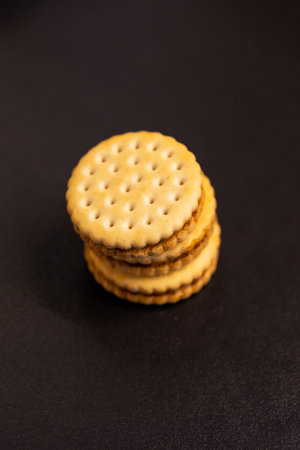 A top down vertical closeup of delicious round cookies with holes stacked on top of each other on a kitchen counter. The tasty snack has a biscuit on each side and is filled with chocolate cream.の写真素材