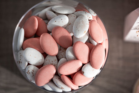 A top down view of a glass bowl full of a typical Belgian treat called sugar beans. The candy is pink and white and is chocolate coated with hard sugar. Sometimes there is a nut inside of it.の写真素材