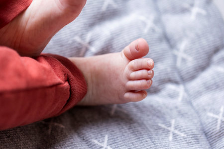 A closeup portrait of only one foot of a newborn baby lying on a gray cushion. The tiny toes are very cute.の写真素材