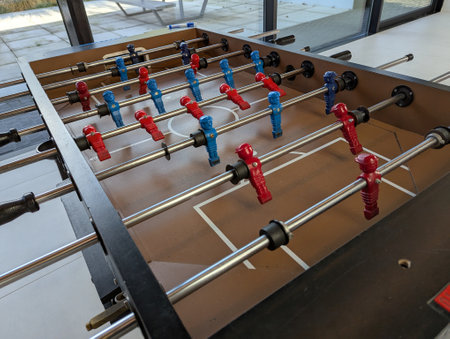 A top down portrait of a foosball table in a café, all the miniature plastic soccer or football players are visible and the handles too. They are ready to be played with.の写真素材