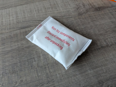 Close-up of a silica gel packet on a wooden table, used for dehumidifying and keeping package contents dry, preventing moisture damage and spoilage.の写真素材
