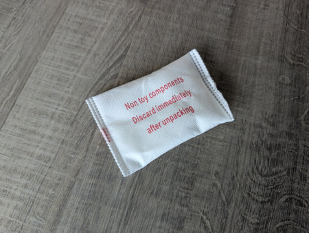 Close-up of a silica gel packet on a wooden table, used for dehumidifying and keeping package contents dry, preventing moisture damage and spoilage.の写真素材