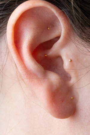 Macro portrait of female ear with auricular acupressure seeds, a non-invasive therapy rooted in...