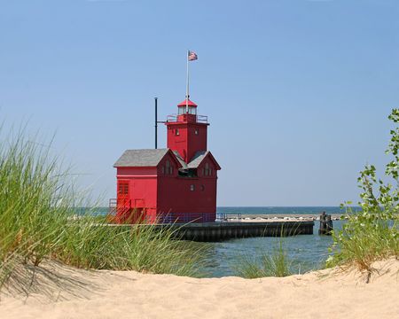 Red lighthouse with American flag.  Beach in the foreground.の写真素材