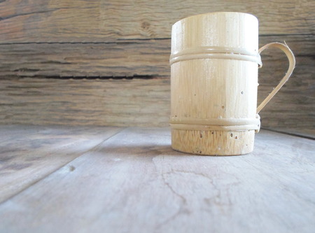 Cups made of bamboo placed on a wooden table with a background of wood. Use a little light coming from the right side of the image. With copy spaceの写真素材