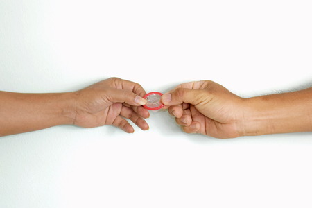 Hand holding a condom on a white background. /Represents emotions and ideas. /Selective focus.の写真素材