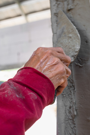 builder worker plastering facade house building with putty knife floatの写真素材