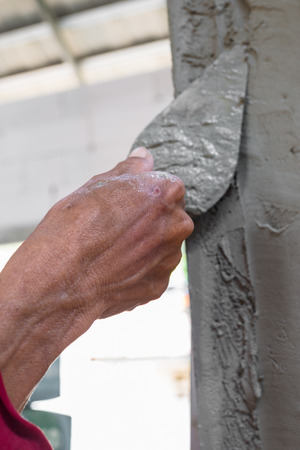 builder worker plastering facade house building with putty knife floatの写真素材