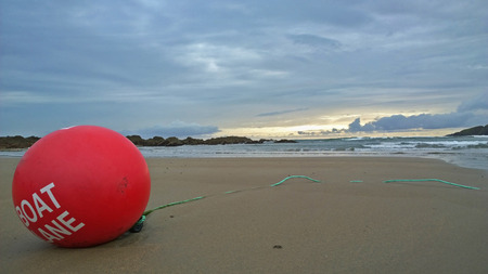 Bantham beach, Devon, United kingdom - June 9, 2014:  showing a ski buoy which marks out a ski lane for water sports, jet skis and boats, with a surfer in the background,のeditorial素材